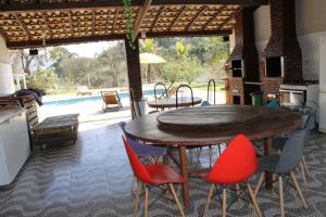 - une table et des chaises en bois sur une terrasse avec piscine dans l'établissement Chalé Canto da Seriema, à Joanópolis