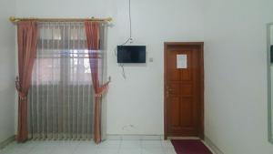um quarto com uma porta e uma televisão na parede em Villa Pakis Residence Banyuwangi em Banyuwangi