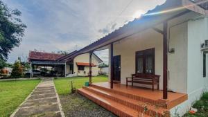 a house with a porch with a bench on it at Villa Pakis Residence Banyuwangi in Banyuwangi