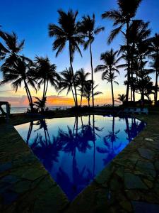 una piscina con palmeras y el océano al atardecer en WOW location Kite Beach Oceanfront 2 Bedroom Patio and Pool, en Cabarete