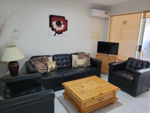 a living room with a black leather couch and a coffee table at Joondalup Apartment in Perth