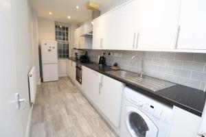 a white kitchen with a sink and a dishwasher at Modern 2 Bed Close to City in London