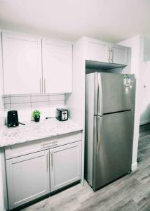 una cocina con nevera de acero inoxidable y armarios blancos en 1 bedroom 2 beds premium suite Startlight Haven, en Calgary