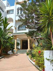 un gran edificio blanco con palmeras y flores en Hôtel Romane en Hammamet