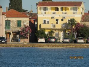 a yellow building with cars parked next to the water at Apartments Renjak in Sukošan