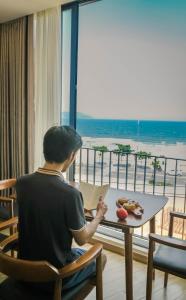 峴港的住宿－Anstay Beach Da Nang，坐在桌子上读书的人
