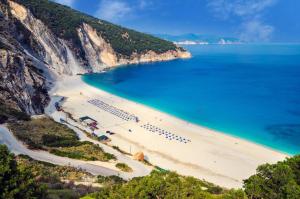 a beach with a group of umbrellas and the ocean at Perfetto Country House - Myrtos View in Anomeriá