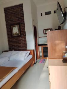 1 dormitorio con cama y pared de ladrillo en Rumah Jati Bantul, en Jarakan