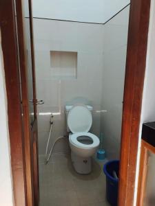 a bathroom with a toilet and a blue bucket at Rumah Jati Bantul in Jarakan