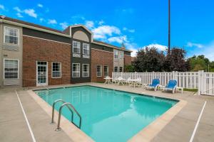 a swimming pool with blue chairs and a building at Quality Inn Mystic-Groton in Mystic