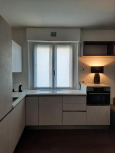 una cucina con armadietti bianchi e una finestra di Locazione Turistica La Rosa - Navigatori a Verona