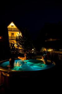 three people swimming in a hot tub at night at Willa Biała Magnolia in Nowy Targ