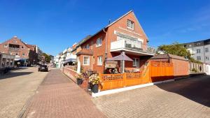 ein Backsteingebäude mit einem orangenen Zaun auf einer Straße in der Unterkunft Ferienwohnung Gartenlaube in Borkum