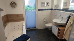 a bathroom with a tub and a sink and a toilet at Ferienhaus Landgang in Kappeln +16 photos