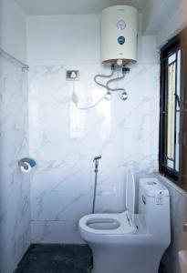 a white bathroom with a toilet and a window at Bastola Basthan Homestay in Darjeeling