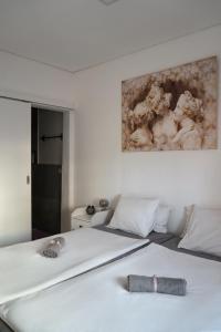 a white bed in a bedroom with a painting on the wall at Casa Silva Diamond in Pinhal Novo