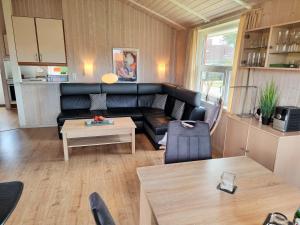 a living room with a black leather couch and a table at Ferienhaus Strandblick 13 in Brodersby +12 photos