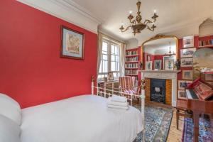 een rode slaapkamer met een bed en een open haard bij The Grand "Old Boy" - Marylebone - by Frankie Says in Londen