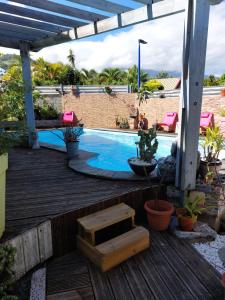 a swimming pool on a wooden deck with plants at Tranquillité in Saint-Joseph