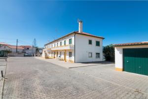 uma rua vazia com um edifício branco com uma garagem verde em Tilli'n'Joe's Beach House em Atouguia da Baleia