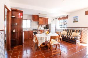 eine Küche und ein Wohnzimmer mit einem Tisch und einem Sofa in der Unterkunft Tilli'n'Joe's Beach House in Atouguia da Baleia