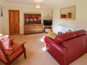 a living room with a red couch and a television at Hill Top Cottage in Welbourn