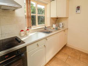 cocina con armarios blancos, fregadero y ventana en Hill Top Cottage, en Welbourn