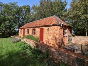 Welbourn的住宿－Hill Top Cottage，院子里有红门的砖砌建筑