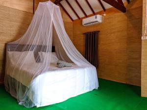 a bed with a mosquito net in a room at Black Sweet Bungalow in Gili Air