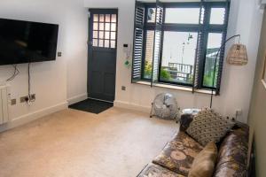 a living room with a couch and a flat screen tv at Seafront Cottage - The Nook in Cardiff