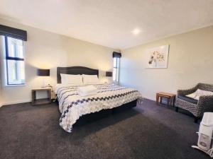 a bedroom with a large bed and a chair at White Stone Apartment in Lake Tekapo