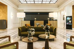 a lobby with a couch and two tables with flowers at Hotel Saski Krakow Curio Collection by Hilton in Kraków