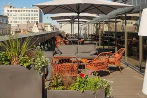 eine Terrasse mit Stühlen, Tischen und Sonnenschirmen auf einem Gebäude in der Unterkunft Aston Hotel Riga in Riga