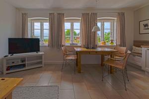 a living room with a dining room table and a television at Ferienwohnung Rüm Hart in Hattstedtermarsch