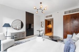 - une chambre avec un lit blanc et un salon dans l'établissement Nasma Luxury Stays - Sophisticated Studio Apartment near Burj Khalifa, à Dubaï
