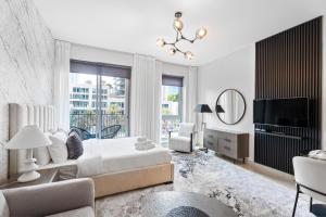 - une chambre blanche avec un lit et une télévision dans l'établissement Nasma Luxury Stays - Sophisticated Studio Apartment near Burj Khalifa, à Dubaï
