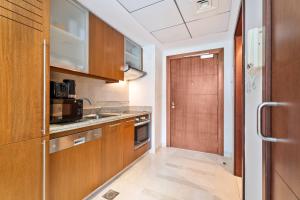 - une petite cuisine avec des placards en bois et une porte dans l'établissement Nasma Luxury Stays - Sophisticated Studio Apartment near Burj Khalifa, à Dubaï