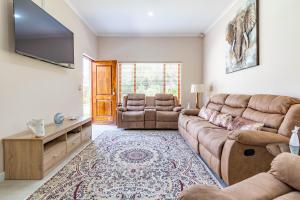 a living room with a couch and a flat screen tv at RSA Lodge in Benoni