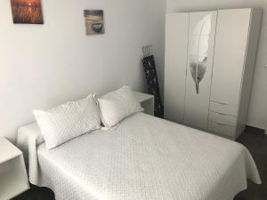 um quarto com uma cama branca e um armário branco em Piedra de la Rendona 2 em Conil de la Frontera