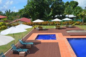una piscina con sillas, mesas y sombrillas en Travellers Point Hotel, en Apia