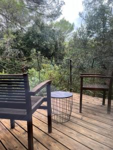 a wooden deck with two benches and a table at La Canopée Private Lodge in Nîmes