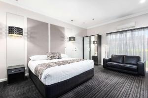 Un dormitorio con una cama y una silla de cuero negro en Comfort Inn Deakin Palms, en Mildura