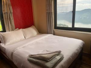 a bed with towels on it in a room with a window at The North Face Inn's Homestay in Pokhara