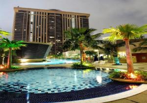 a large pool with palm trees in front of a building at Marmaid Suite At Barjaya Time Square KL in Kuala Lumpur