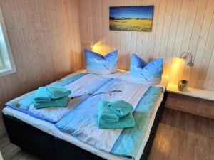 a large bed with blue pillows and towels on it at Ferienhaus Strandliebe in Brodersby