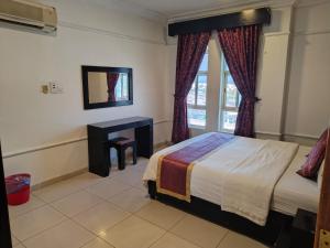 1 dormitorio con cama, escritorio y ventana en منامي للشقق المخدومة-كورنيش الخبر-اقتصادي, en Al Khobar