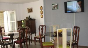 a dining room with a table and chairs and a television at Pousada Vó Irene in Itacuruçá