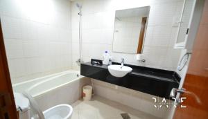 a bathroom with a sink and a toilet and a tub at RARE Holiday Homes Offering Deluxe Studio near City Center Mall in RIMPZ - B2112 in Dubai