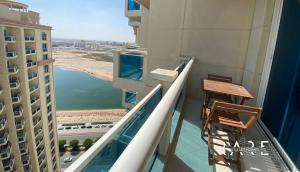 balcón con 2 sillas y vistas al agua en RARE Holiday Homes - Deluxe Studio - Near City Center Mall - IMPZ - R2112 en Dubái