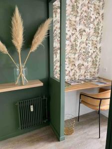 a room with a green wall with a table and a chair at Charmant studio cosy avec parking in Caen
